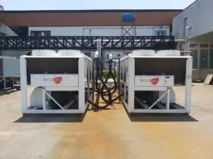 Dois grandes equipamentos de refrigeração da Tecnogera estão posicionados lado a lado em uma área externa, sobre um piso de concreto.