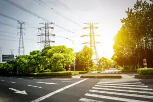 Um cruzamento tranquilo, emoldurado por vegetação e altos postes de eletricidade, destaca a geração de energia elétrica.