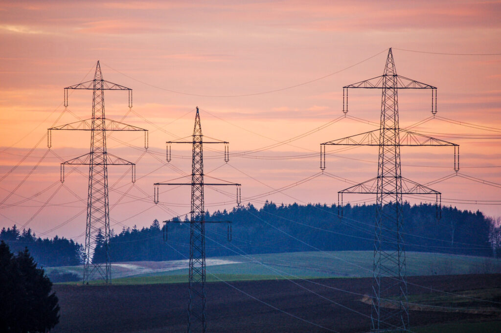 Torres de transmissão destacam-se ao entardecer em paisagem rural, ilustrando a energia descentralizada.