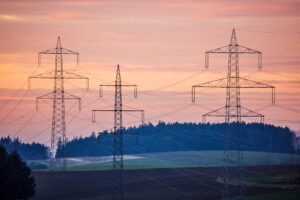 Torres de transmissão destacam-se ao entardecer em paisagem rural, ilustrando a energia descentralizada.